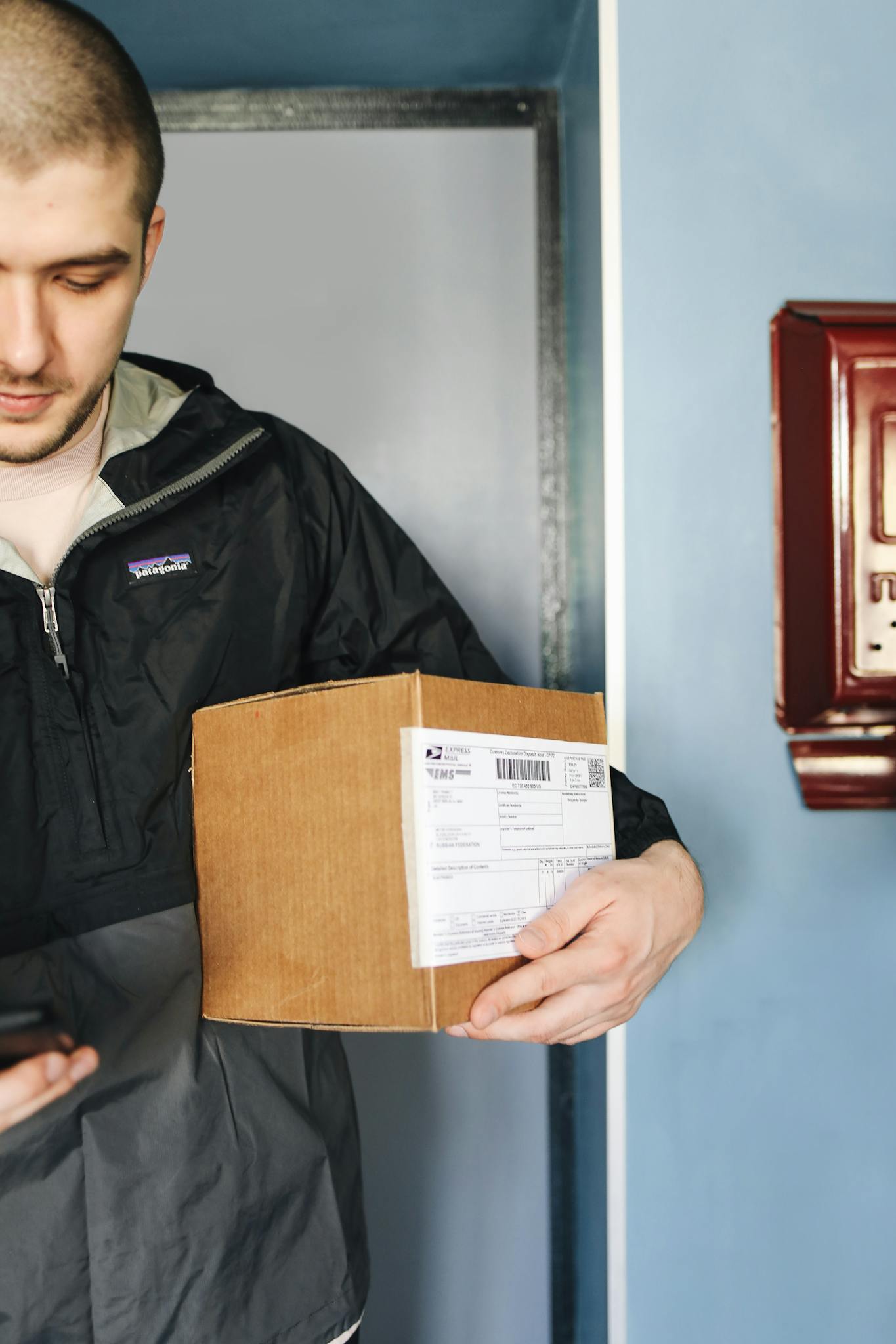 A man holding a cardboard box inside a bright room.